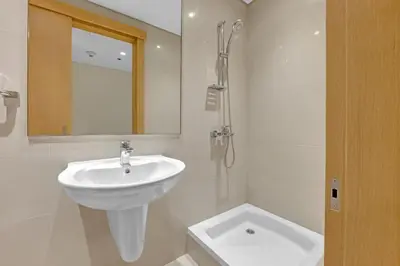 a white bathroom with a sink and a mirror at Neat 3BR Habour Views with Balcony-Burj Khalifa View, Pool, Gym and Modern Facilities in Dubai