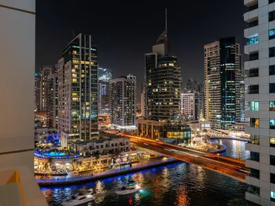 a city skyline at night with a river and buildings at Livora Stays - Dubai Marina With Balcony & Water Views in Dubai