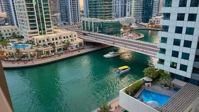 a bridge over a river in a city with a boat at Livora Stays - Dubai Marina With Balcony & Water Views in Dubai