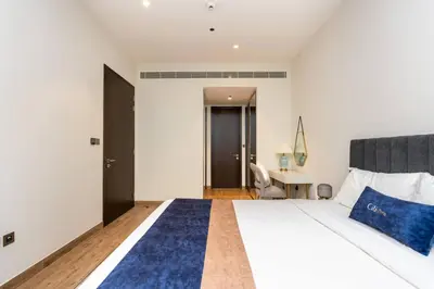 a bedroom with a bed with blue pillows and a desk at CitiHome - Iconic 1BR Jumeirah Living Marina Gate in Dubai