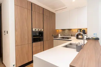 a kitchen with white counters and wooden cabinets at CitiHome - Iconic 1BR Jumeirah Living Marina Gate in Dubai
