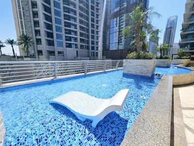 a swimming pool with a white chair in a city at Newly Upgraded 3-BR close to Barasti Beach in Dubai