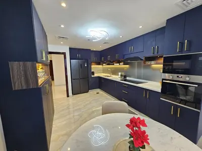 a kitchen with blue cabinets and a table with red flowers at Newly Upgraded 3-BR close to Barasti Beach in Dubai