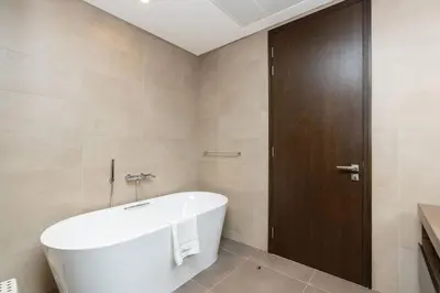 a bathroom with a white tub and a wooden door at CitiHome - Elegant Retreat in Dubai Marinas Heart in Dubai