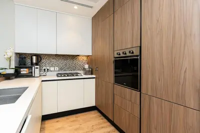 a kitchen with white counters and wooden cabinets at CitiHome - Elegant Retreat in Dubai Marinas Heart in Dubai