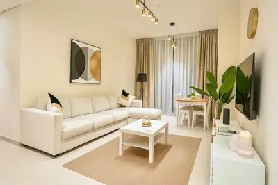 a living room with a white couch and a table at 2BR Luxury, 2,5 bath, Baby bed, Gym & Pool in Dubai