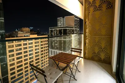 a balcony with two chairs and a wooden bench on a building at 2BR Luxury, 2,5 bath, Baby bed, Gym & Pool in Dubai