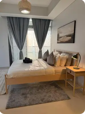 a bedroom with a large bed with a lamp and a table at 3 bedroom 51st floor Panoramic ocean views in Dubai