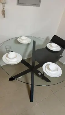 a glass table with three plates on top of it at Cozy Studio Apartment in JCV in Dubai