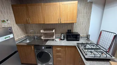 a kitchen with a stove and a sink and a microwave at Cozy Studio Apartment in JCV in Dubai