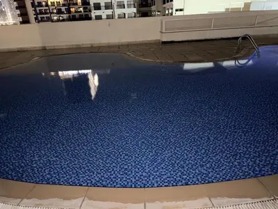 a swimming pool in a building with a blue floor at Cozy Studio Apartment in JCV in Dubai