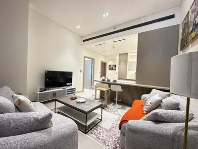 a living room with two couches and a television at Luxury 1BR - Private Balcony Pool & Smart Home - Binghatti Phantom JVC in Dubai