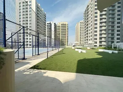 a large field of grass in a city with tall buildings at Luxury 1BR - Private Balcony Pool & Smart Home - Binghatti Phantom JVC in Dubai