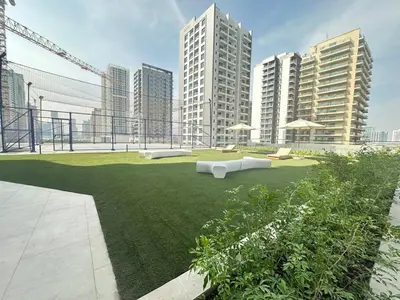 a grassy area with two white couches and some buildings at Luxury 1BR - Private Balcony Pool & Smart Home - Binghatti Phantom JVC in Dubai