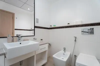 a white bathroom with a sink and a toilet at Gala Guests - Signature Skyview Tower High-Floor Marina Living in Dubai