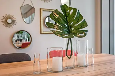 a table with three glass vases and a potted plant at StayShort - Bluewaters Finest Elegant 1BR Apartment - Beach Lifestyle in Dubai