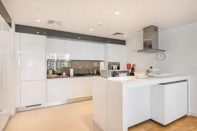 a white kitchen with white cabinets and appliances at StayShort - Bluewaters Finest Elegant 1BR Apartment - Beach Lifestyle in Dubai