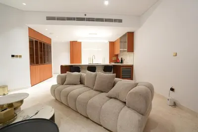 a living room with a couch and a kitchen at Spacious 2BR Near Beach Ellington in Dubai