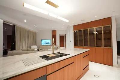 a kitchen with wooden cabinets and a living room at Spacious 2BR Near Beach Ellington in Dubai