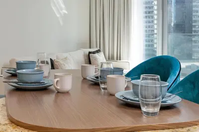a wooden table with plates and glasses on it at Imperial Avenue Downtown Lux 1Bed with Balcony in Dubai
