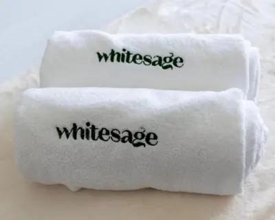 two white towels with the word wilderness written on them at Imperial Avenue Downtown Lux 1Bed with Balcony in Dubai