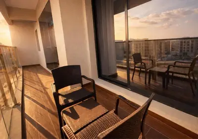 a room with a balcony with chairs and a large window at Stylish & Cozy 2BR Apartment in Liwan 2 in Dubai