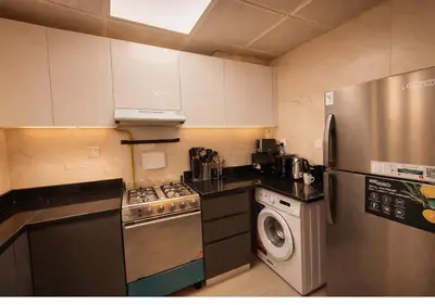a small kitchen with a stove and a refrigerator at Stylish & Cozy 2BR Apartment in Liwan 2 in Dubai