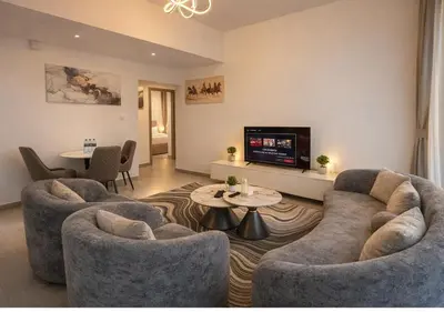 a living room with two couches and a tv at Stylish & Cozy 2BR Apartment in Liwan 2 in Dubai