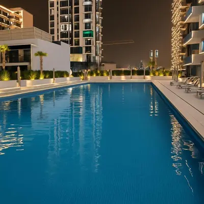 a large swimming pool in a city at night at Cozy 1-Bedroom Flat in Central JVC in Dubai
