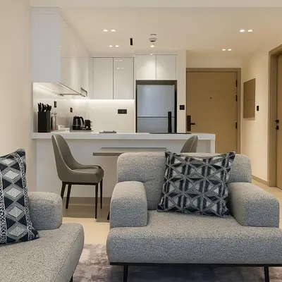 a living room with a couch and a kitchen at Cozy 1-Bedroom Flat in Central JVC in Dubai