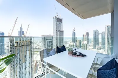 a balcony with a white table and chairs and a view of the city at Vogue Downtown Opera Grand near Burj Khalifa and Dubai Mall, Two Bedroom Apartment with Large Balcony and Access to all Amenities in Dubai