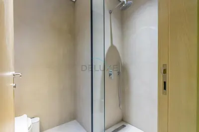 a shower with a glass door in a bathroom at Balcony-Facing Pool 2BR with Assistant Room, Minutes Walk to Park, Miracle and Butterfly Garden, Divine Living, Arjan by Deluxe Holiday Homes in Dubai