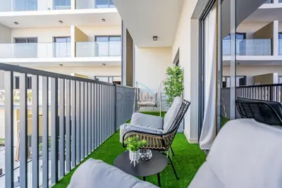 a balcony with a bed and a chair and a table at Balcony-Facing Pool 2BR with Assistant Room, Minutes Walk to Park, Miracle and Butterfly Garden, Divine Living, Arjan by Deluxe Holiday Homes in Dubai