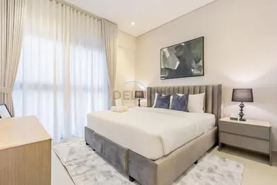 a bedroom with a large bed and a large window at Balcony-Facing Pool 2BR with Assistant Room, Minutes Walk to Park, Miracle and Butterfly Garden, Divine Living, Arjan by Deluxe Holiday Homes in Dubai