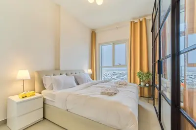 a white bedroom with a large bed and a window at Chic & Modern 1BR Stay in Collective Dubai Hills in Dubai