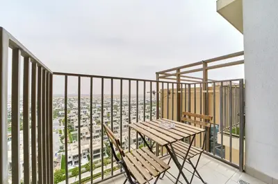 a balcony with a table and chairs and a view at Chic & Modern 1BR Stay in Collective Dubai Hills in Dubai
