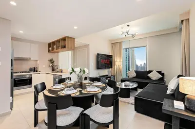 a kitchen and a living room with a table and chairs at Luxury 2BR Downtown Steps from Burj Khalifa in Dubai