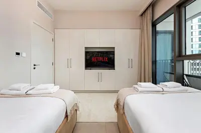 two white beds in a room with a tv at Luxury 2BR Downtown Steps from Burj Khalifa in Dubai