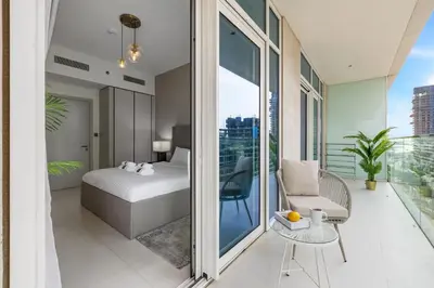 a bedroom with a bed and a chair on a balcony at BLVD-Beachfront Luxe Stay with Private Beach Access in Dubai