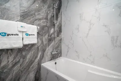 a bathroom with a white tub and a marble wall at HiGuests - Charming Studio with Lake Views in Business Bay in Dubai