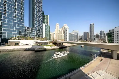 a boat in a river in a city with tall buildings at Luxury Bluewater Escape 1BR Canal view 5242T in Dubai