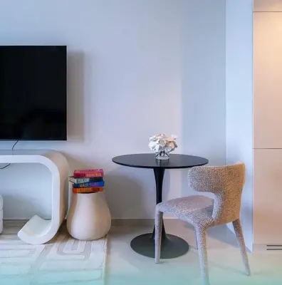 a table and chair in a room with a tv at Luxury Studio With Pool View Near Burj Khalifa in Dubai
