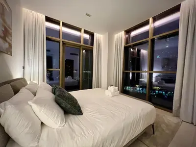 a bedroom with a white bed and a large window at Modern 2-Bedrooms Apartment with Stunning Marina Views in Dubai