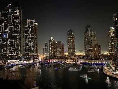 a city skyline at night with boats in the water at Modern 2-Bedrooms Apartment with Stunning Marina Views in Dubai