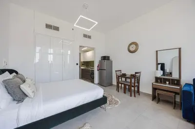 a bedroom with a bed and a desk and a kitchen at Daniels Studio at V2 Residence, Sports City in Dubai