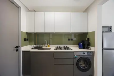 a kitchen with white cabinets and a washing machine at Daniels Studio at V2 Residence, Sports City in Dubai