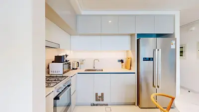 a kitchen with white cabinets and a stainless steel refrigerator at Chic 2BR Getaway Marina Vista T2 Sea view in Dubai