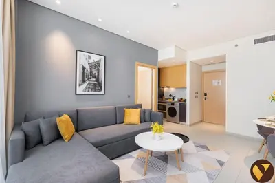 a living room with a couch and a table at Vogue JVT Novotel near Springs Souk Mall, One Bedroom apartment with Balcony and Vibrant Community View, Access to all Amenities in Dubai
