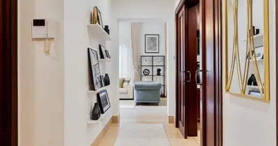 a hallway with white walls and a blue chair at Downtown 2BHK Burj View & Private Garden in Dubai