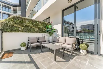 a patio with a couch and chairs on a building at Inviting Studio Overlooking the Pool, Just a Short Drive from Dubai Autodrome, Samana Golf Avenue, Dubai Studio City by Deluxe Holiday Homes in Dubai